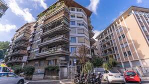 A multi-story residential building with balconies, a parking sign, and parked cars. - Musei Vaticani Apartamento per 8 persone (Rome)