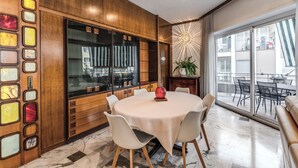 A modern dining area with a round table, white chairs, and a wooden cabinet with glass doors. - Musei Vaticani Apartamento per 8 persone (Rome)