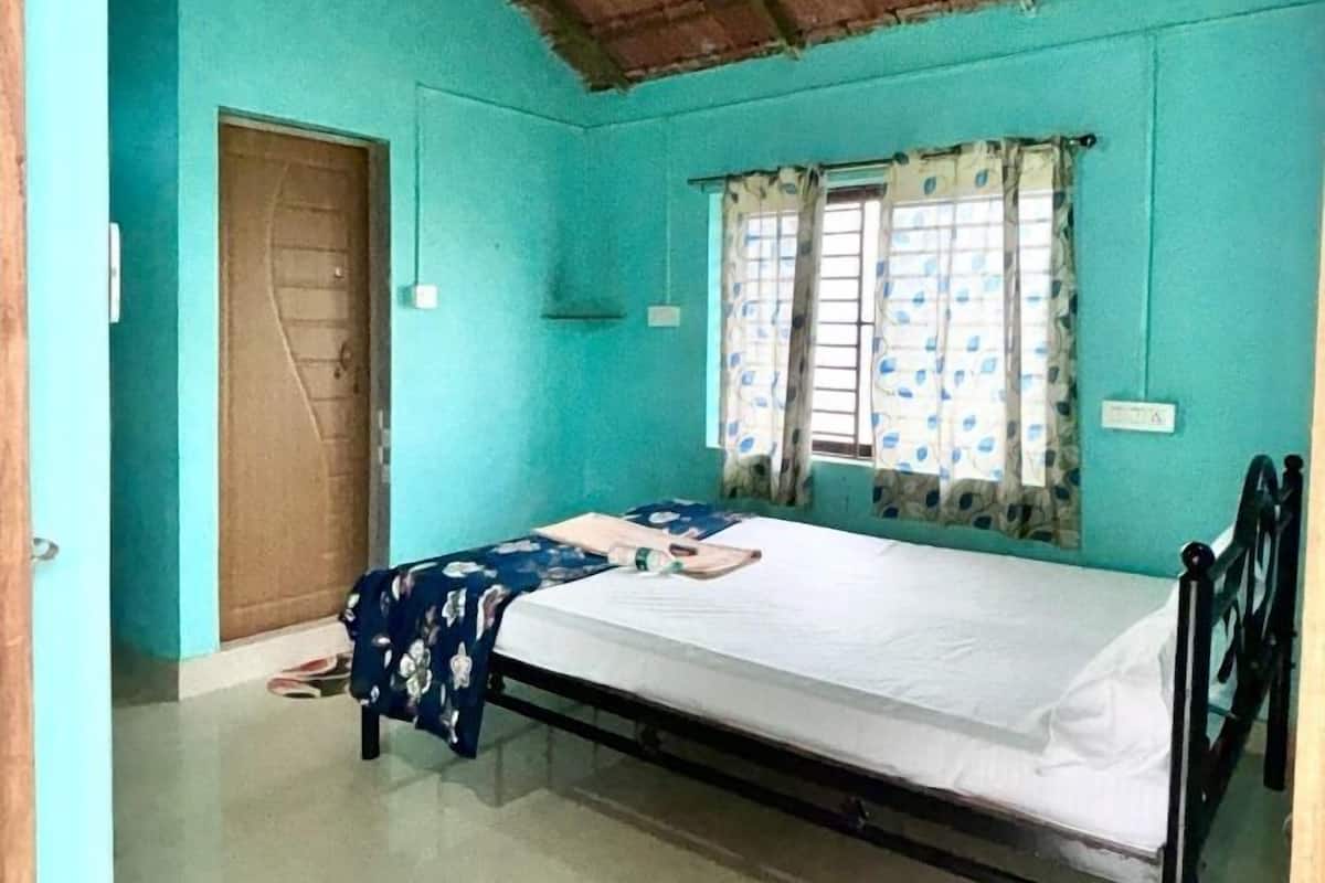 Une chambre avec un lit simple, un plafond en bois et une fenêtre ornée de rideaux à motifs.