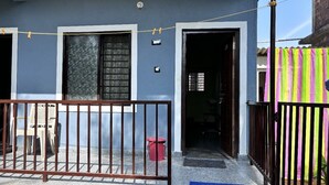 Un immeuble résidentiel à la façade bleue, doté d’une entrée sécurisée par un portail et d’une poubelle visible.