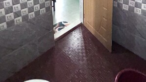 Une salle de bain avec un mur en marbre, une porte en bois et un carrelage à motifs à carreaux.