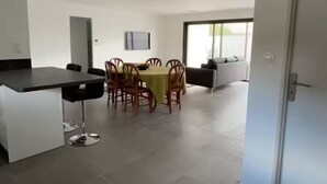 Una cucina moderna con zona pranzo, caratterizzata da un'isola centrale, sedie e un divano.