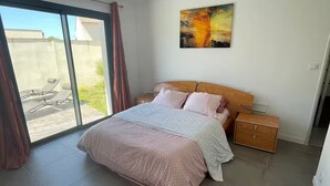 Camera da letto con un letto, un comodino, un quadro e una porta scorrevole in vetro che dà su un patio.