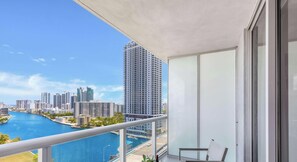 Un balcon offrant une vue sur le paysage urbain, une rivière et un immeuble de grande hauteur.