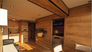 Een modern interieur met houten wanden, een eethoek met stoelen en borden, en een keuken met kastjes en een koelkast.