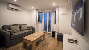 A modern living room with a grey sofa, wooden coffee table, and a mounted TV displaying a Netflix interface. - SnowGranada Los Valles Alodia Parking+Chair (Sierra Nevada)