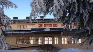 A building with a covered entrance, steps leading up to it, and snow on the ground. - SnowGranada Los Valles Alodia Parking+Chair (Sierra Nevada)