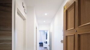 A hallway with wooden flooring, a metal rack, and a wooden door. - SnowGranada Los Valles Alodia Parking+Chair (Sierra Nevada)