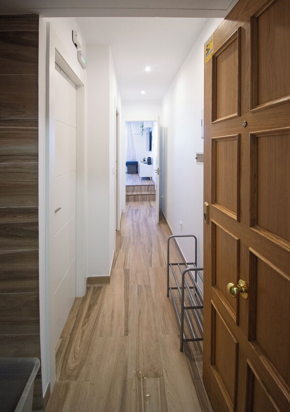 A hallway with wooden flooring, a metal rack, and a wooden door.