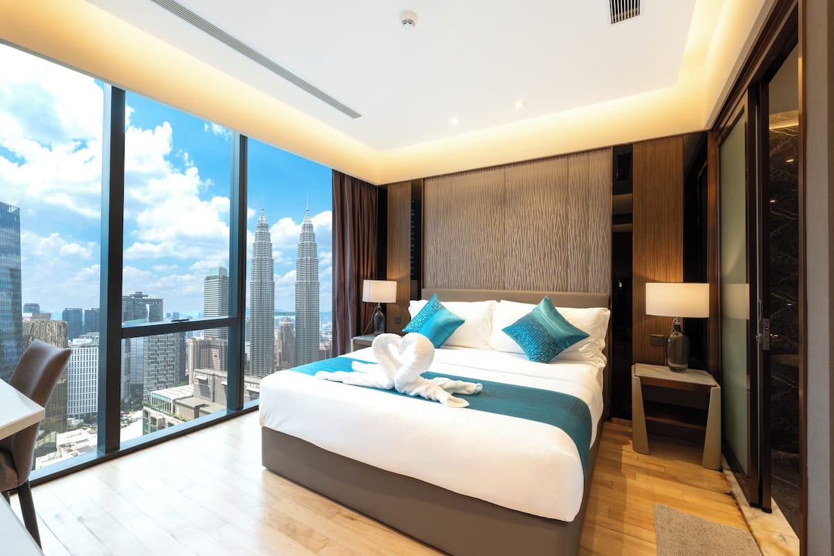 Une chambre d’hôtel moderne dotée d’un grand lit, d’un bureau et offrant une vue sur le paysage urbain.