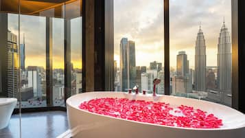 A bathroom with a bathtub filled with rose petals, a large window with a cityscape view, and a modern design.