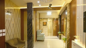 A hotel lobby with a sofa, a reception desk, and a ceiling fan.