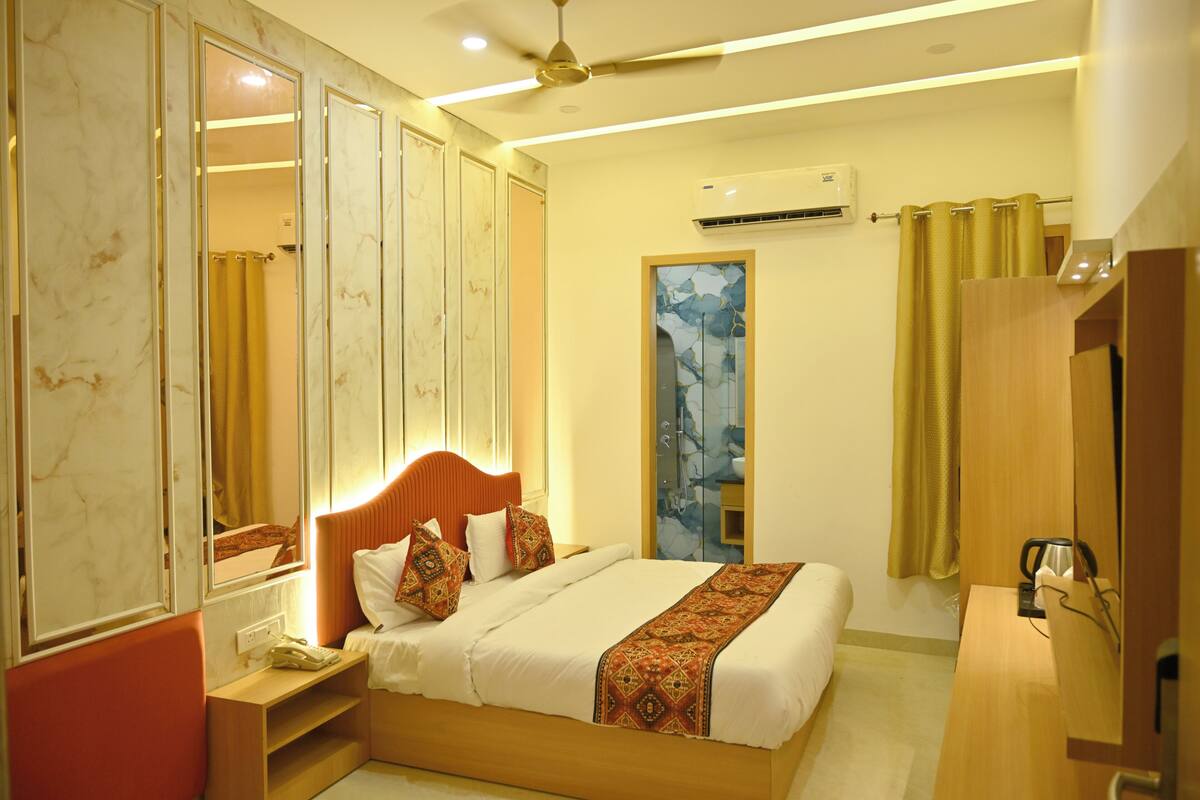 A hotel room with a bed, bedside table, nightstand, wardrobe, and a mirror.
