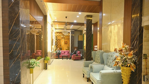 A lobby with a marble reception desk, plush seating, and a chandelier.