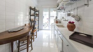 Una cocina con paredes de azulejos blancos, una mesa de comedor de madera y un horno empotrado.