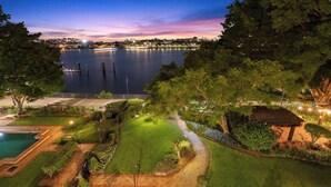 A landscaped garden with a swimming pool, a gazebo, and a view of a lake at dusk. - Luxury Water Views ~ 2Bed/2Bath/1Car/Pool (Teneriffe)