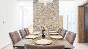 Ein Esszimmer mit einem langen Tisch, gedeckt für sechs Personen, einer Weinflasche und Gläsern.