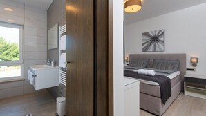 Ein modernes Schlafzimmer mit einem Bett, Nachttischen und einem großen Fenster.