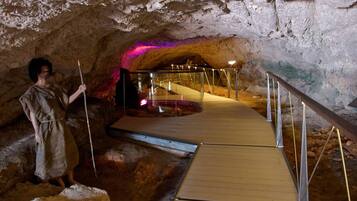 Eine Höhle mit einem Holzsteg und Metallgeländern, der zu einer Plattform mit einer Glaseinfriedung führt.