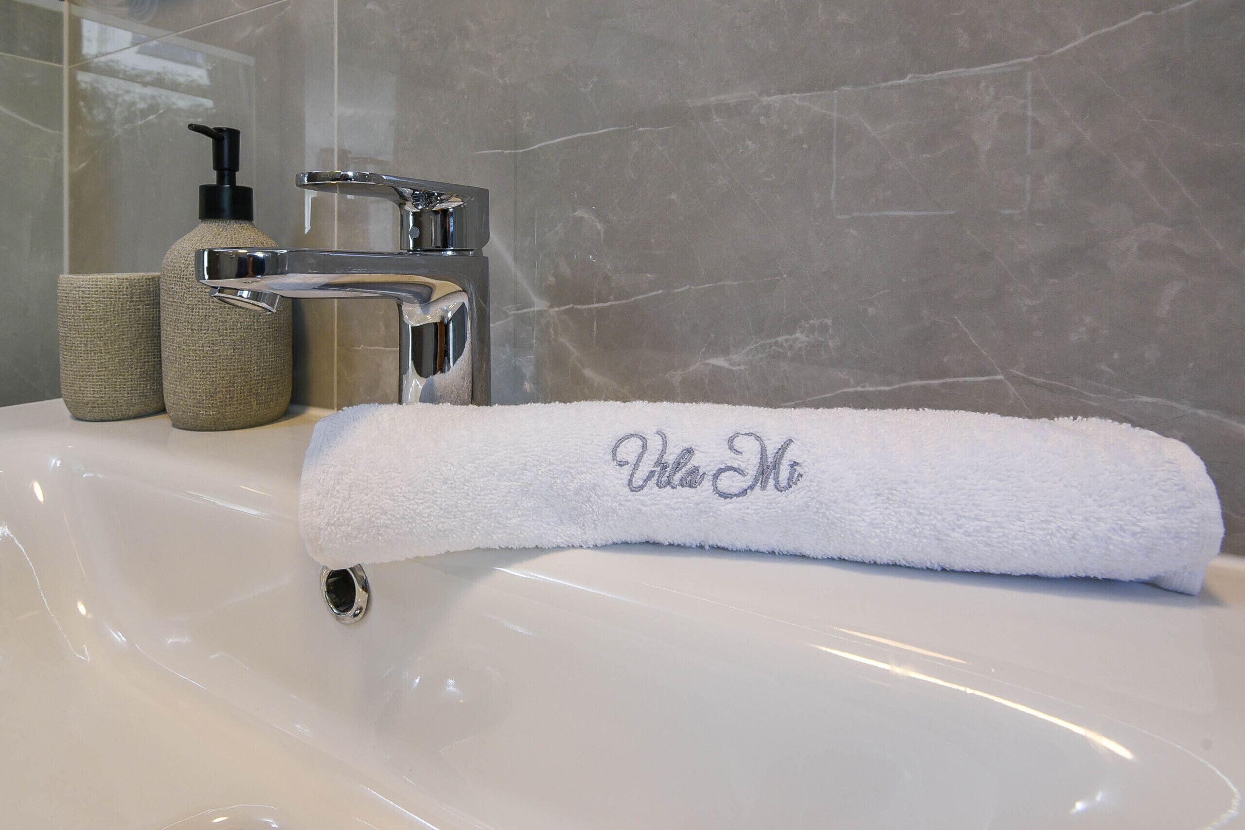 A white bathtub with a towel labeled "Villa Mo" and a bottle of soap.