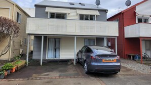 Een tweelaags woonhuis met een grijze auto op de oprit.