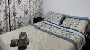 Een slaapkamer met een bed, kussens, een deken en een hoofdeinde.