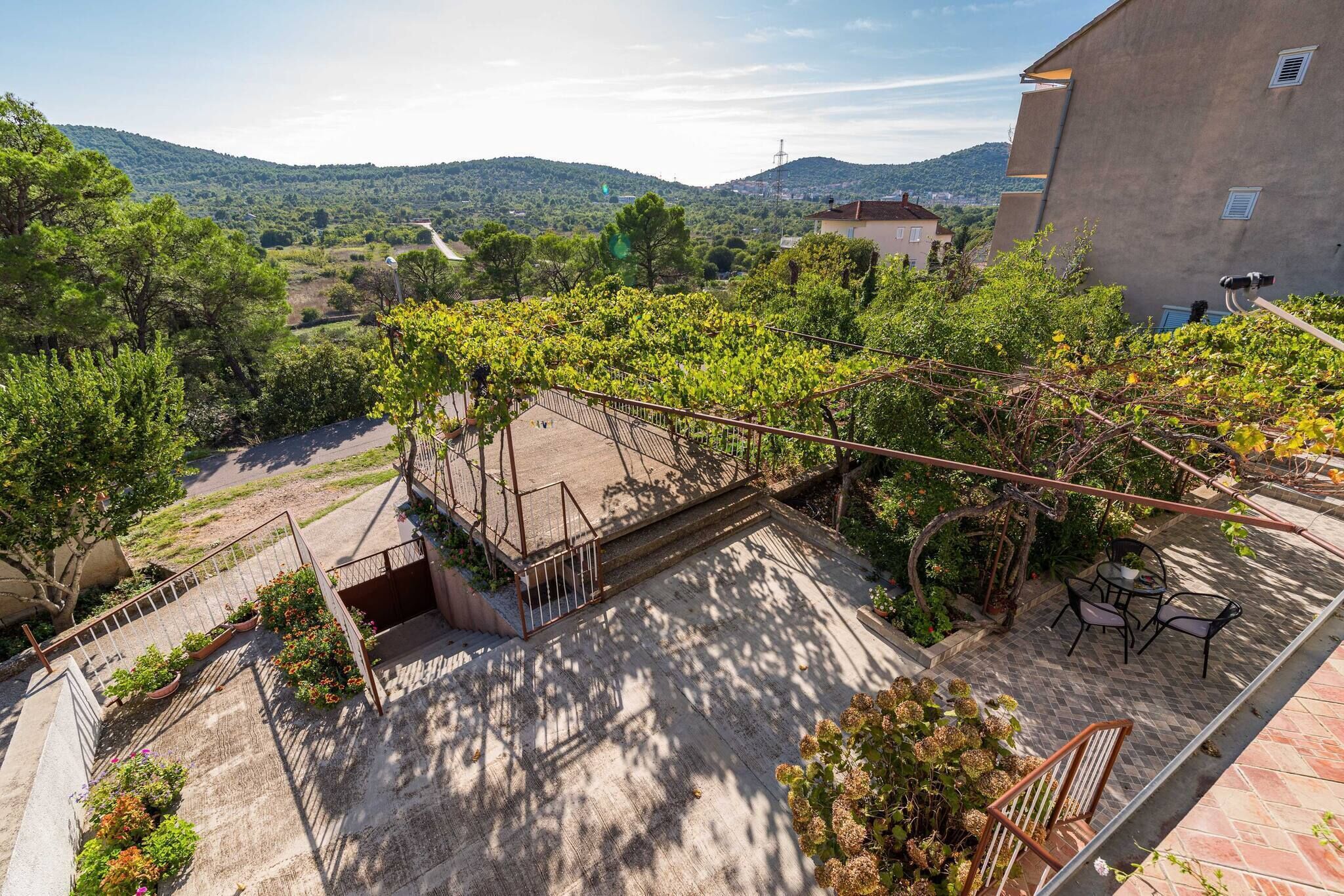 A rooftop terrace with a pergola, outdoor seating, and a view of the surrounding landscape.