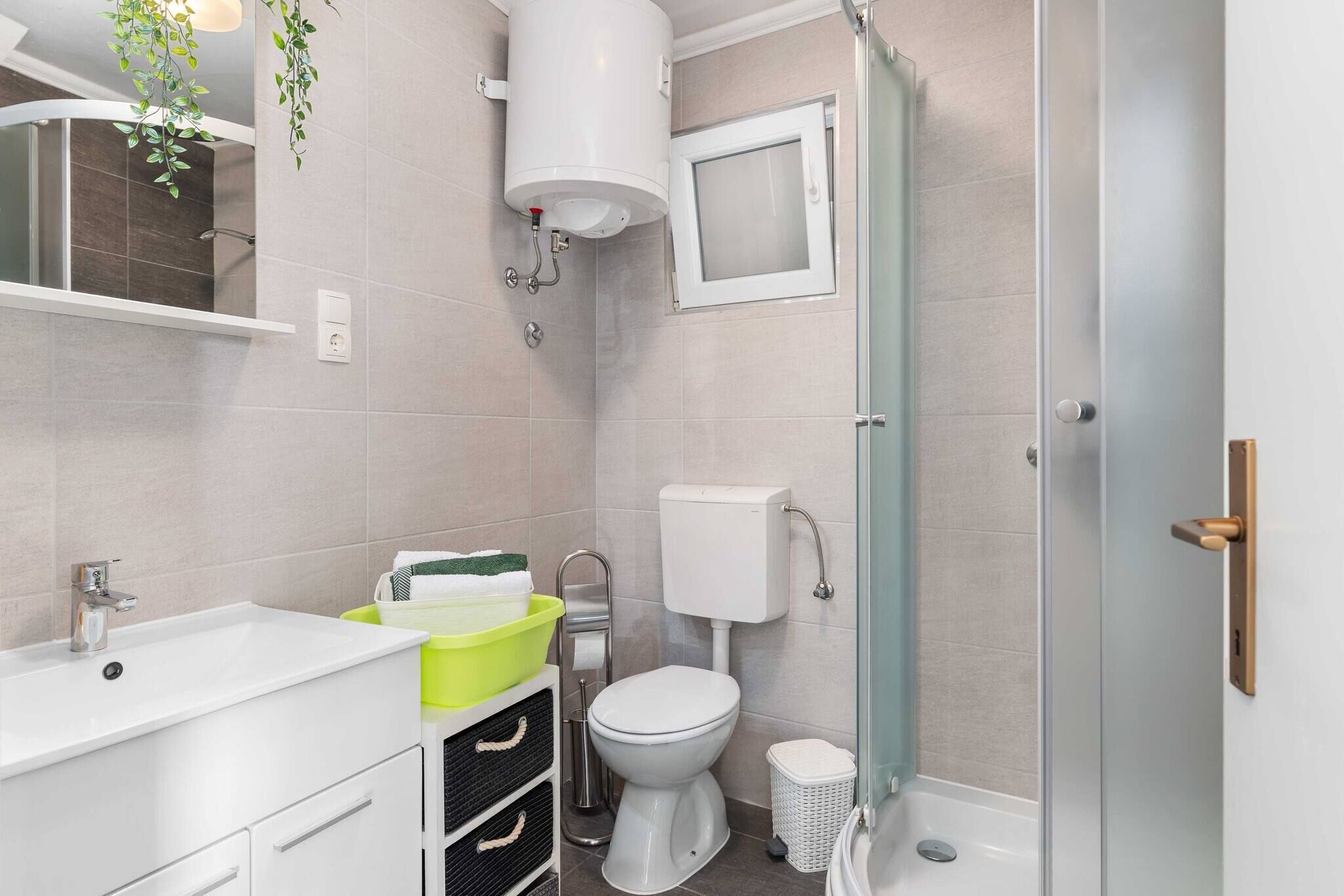 A modern bathroom with a white sink, a toilet, and a shower area.