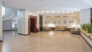 A spacious lobby with a central seating area, a staircase, and a reception desk.
