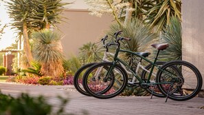 Ein Fahrrad, das an einem Gebäude geparkt ist, mit einem Garten im Hintergrund.