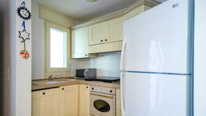 A compact kitchen with light-colored cabinets, a built-in oven, a microwave, and a refrigerator. - Villa Luna 20 meters from the sea in Punta Prosciutto (Punta Prosciutto)