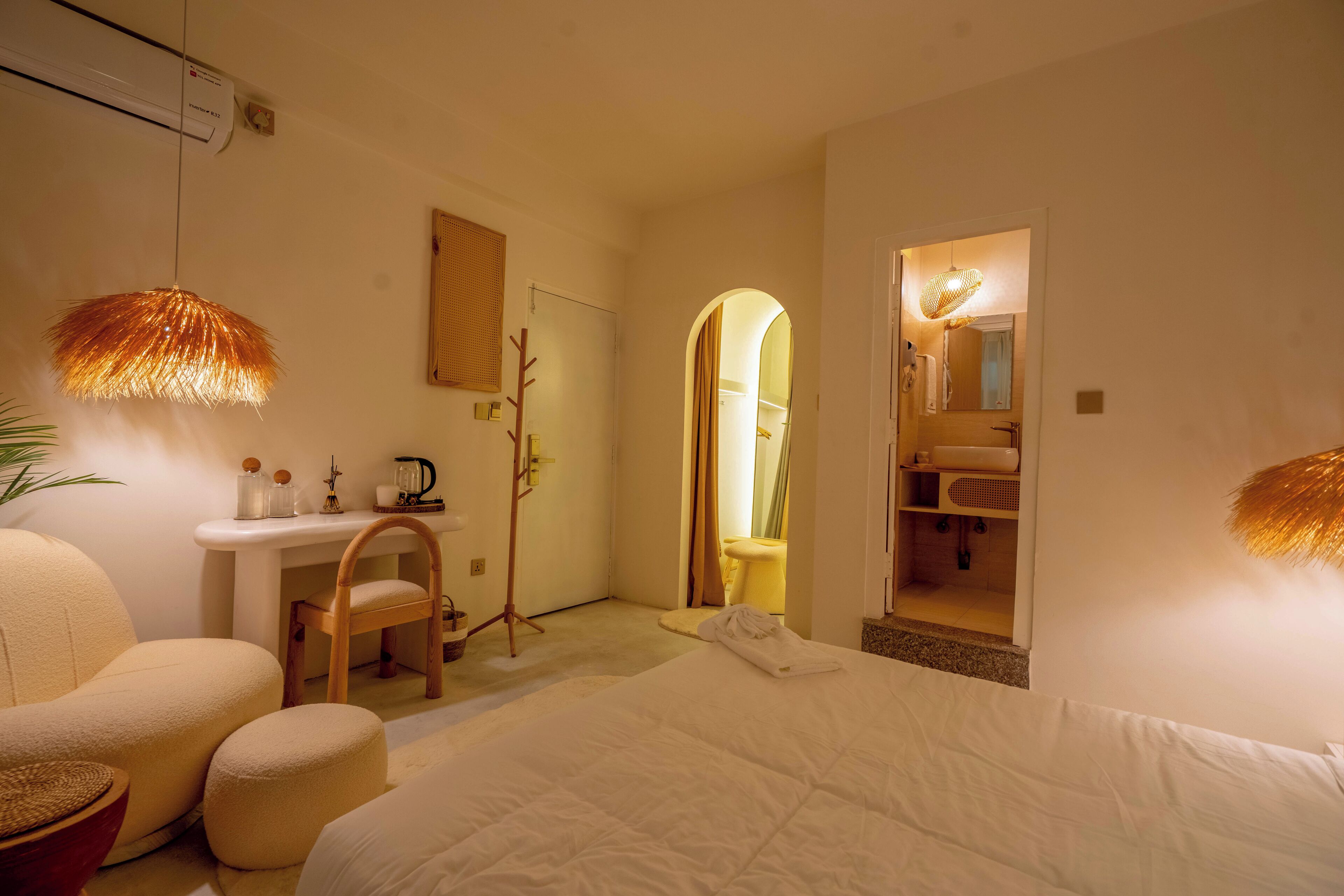 A hotel room with a bed, a desk, a chair, and a bathroom visible through an archway.