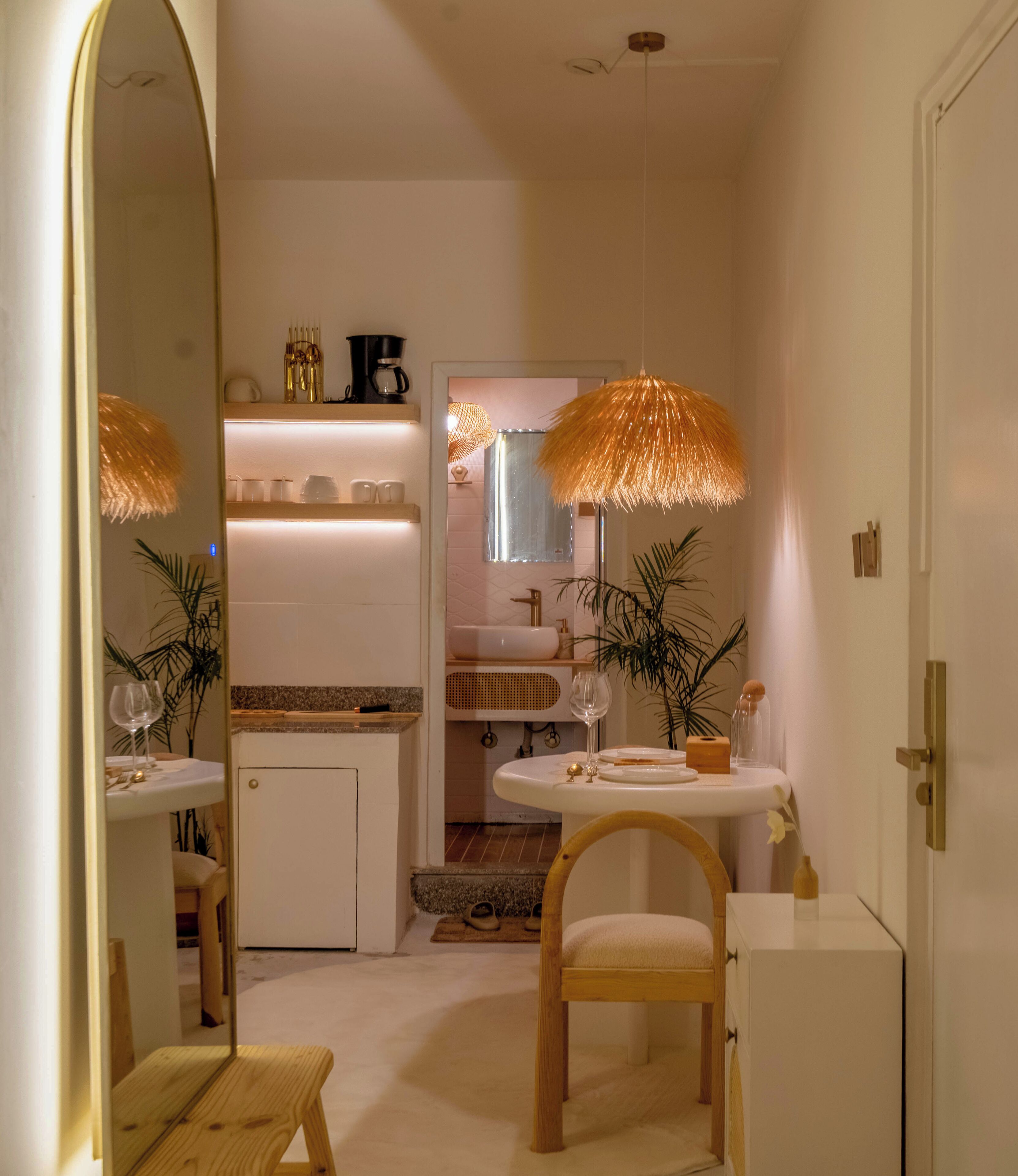 A compact kitchen with a white sink, wooden chair, and a dining table.