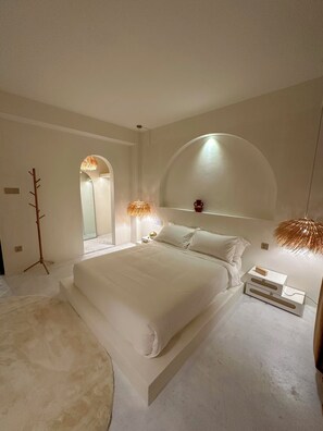A modern bedroom with a large bed, a bedside table, a lamp, and a coat rack. - Lagom Premium Apartment Pvt Ltd (Nagarjun)