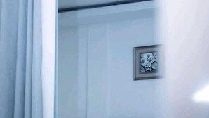 Un dormitorio con una cama, cabecera, un cuadro en la pared y un ventilador de techo.