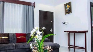 Una sala de estar moderna con un sofá gris oscuro, una mesa de centro de vidrio y una orquídea en maceta.