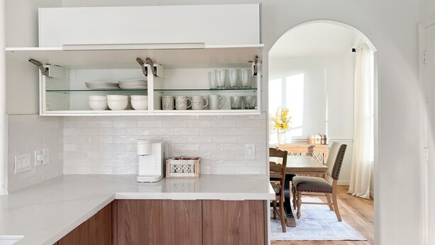 A modern kitchen with white cabinetry, a coffee maker, and a glass shelf with dishes and cups. - Charming & Bright Retreat - Luxe Pool - Golf Views! (Humble)
