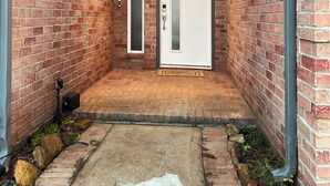 A brick building entrance with a white door, a small archway, and a number '18' sign on the right. - Charming & Bright Retreat - Luxe Pool - Golf Views! (Humble)