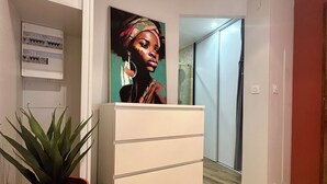 Ein Flur mit einem weißen Schrank, einer Topfpflanze und einem Bild an der Wand.
