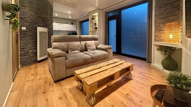 Ein modernes Wohnzimmer mit einer Couch, einem Holztisch und einem großen Fenster mit Blick.