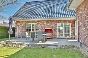 A brick house with a tiled roof, a patio with outdoor furniture, and a large window. - The Nordic Frisian house (Scharbeutz)