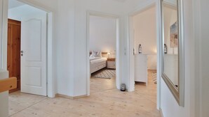 Ein modernes, helles Schlafzimmer mit Bett, Nachttisch und Spiegel.