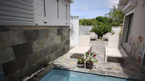 En swimmingpool med väggar av sten och planterade blommor i krukor.