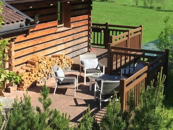 A wooden cabin with a patio area featuring outdoor seating and a fire pit.