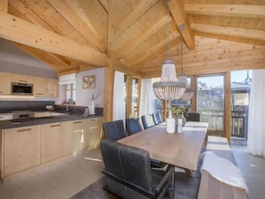 A modern kitchen with wooden cabinets, a built-in oven, and a dining area with a large table and chairs.