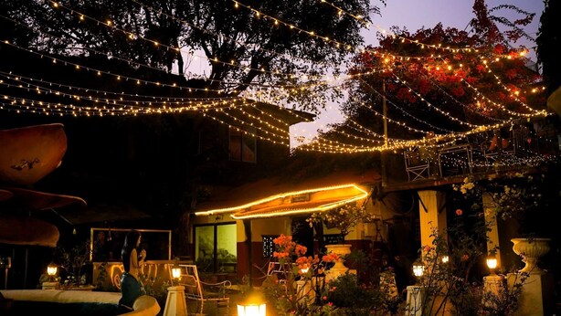 Een terras buiten met lichtjes, een fontein en plantenpotten.