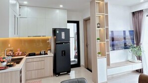 Una cucina moderna con mobili bianchi, un frigorifero nero e un'area pranzo con tavolo e sedie.