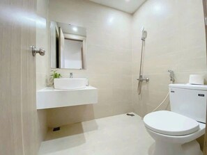 A modern bathroom with a toilet, sink, and shower. - Minh Anh Apartment (Hue)