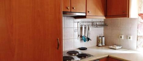Una cucina con mobili in legno, un fornello e uno schienale piastrellato.