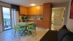 A compact living space with a dining area, kitchenette, and a large sofa.